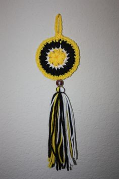 a yellow, black and white tassel hanging from a wall with a circular object in the center