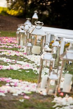 rows of white and pink flower petals on the ground at a wedding ceremony with lanterns