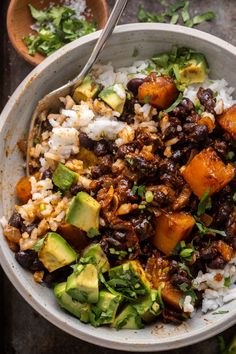 a bowl filled with rice, beans and avocado on top of a table