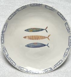 two fish on a white plate with blue trim around the edges and bottom, sitting on a gray surface