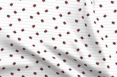 a white sheet with red ladybugs on it and lines in the background, as well as a shadow