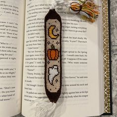 an open book with a beaded bookmark attached to it