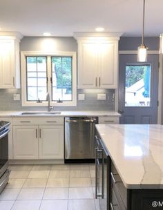 an empty kitchen with stainless steel appliances and white cabinetry, along with marble counter tops