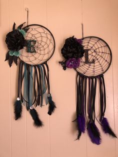 two dream catchers hanging on the wall with flowers and feathers attached to each one