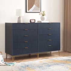 a blue dresser with gold handles in a white living room next to a painting on the wall