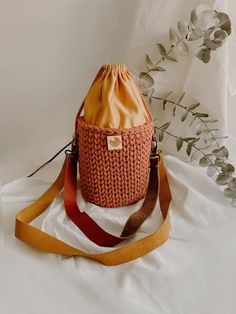 a handbag sitting on top of a white sheet next to a plant with leaves