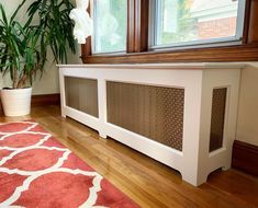 a white radiator sitting on top of a wooden floor next to a window