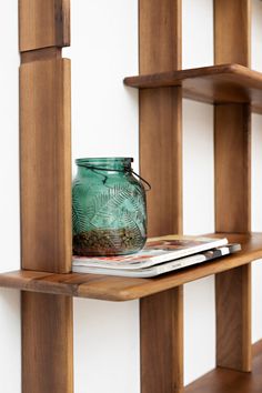 a green jar sitting on top of a wooden shelf next to a stack of books