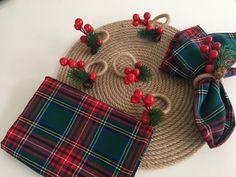 a place mat with red berries and green plaid napkins on it next to a pair of scissors