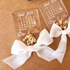 two clear acrylic calendars with white ribbons tied around them