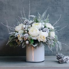 a white vase filled with flowers and pine cones