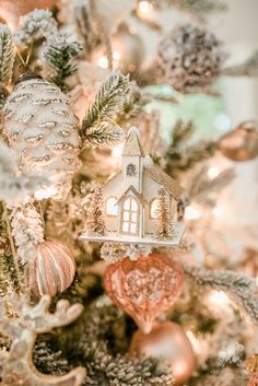 a close up of a christmas tree with ornaments on it and a house ornament