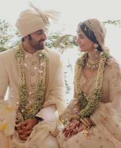 two people sitting next to each other in wedding outfits