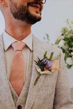 a man wearing a suit and tie with a boutonniere on his lapel