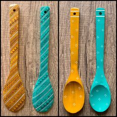 four different colored spoons are lined up on a wooden surface, one is yellow and the other is blue