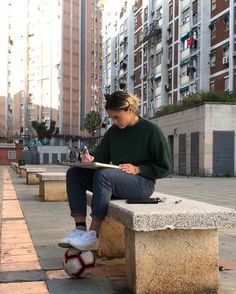 a person sitting on a bench with a book and soccer ball in front of them