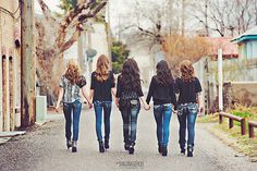 three girls walking down the street holding hands