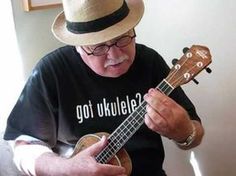 a man wearing a hat and glasses playing an ukulele