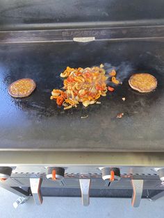 some food is cooking on top of an outdoor bbq grill with two burgers