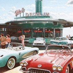 several classic cars are parked in front of a drive - in restaurant on the beach