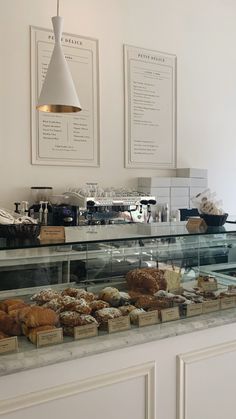 a display case filled with lots of pastries on top of a white counter next to two framed menus