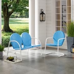 two blue chairs sitting on top of a cement floor next to a potted plant