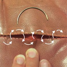 a close up of a person's hand holding a piece of leather with arrows pointing to it