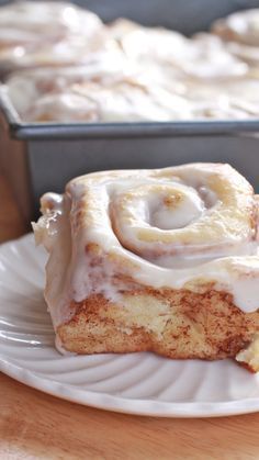 cinnamon rolls on a white plate next to a baking pan