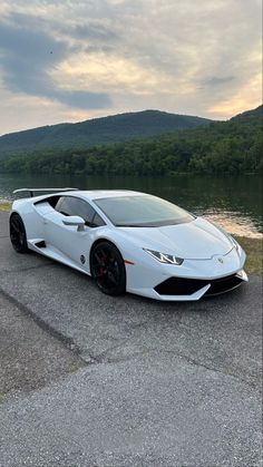 a white sports car parked in front of a lake