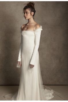 a woman in a white dress with long sleeves and an off the shoulder neckline