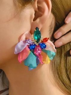 a close up of a person wearing large earrings with colorful flowers on the back of them