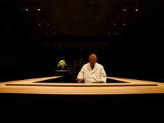 a man sitting in front of a table with a potted plant on top of it