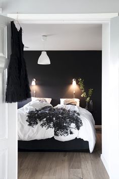 a black and white bedroom with two lamps on either side of the headboard, and an open door leading to another room