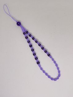 a purple beaded necklace on a white surface