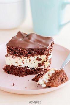 a piece of cake with chocolate frosting on a plate next to a fork and cup