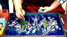 a man is working on an art project with blue and green tiles in front of him