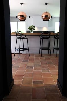 an open door leading into a kitchen with two stools and a bar in the background