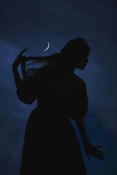 the silhouette of a woman with her hair blowing in the wind, against a night sky