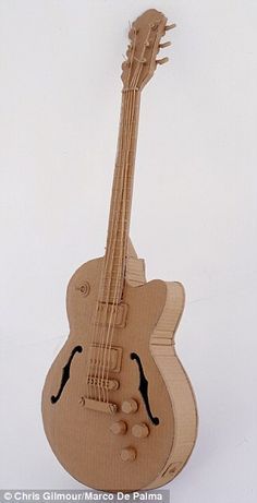 a wooden toy guitar sitting on top of a white surface