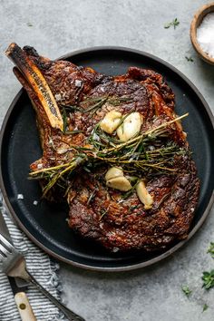 steak with garlic and herbs on a black plate