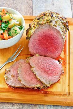 meatloaf with potatoes and carrots on a cutting board next to a bowl of salad