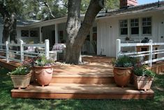 two potted plants are sitting on the steps in front of a white house with trees