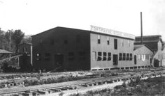 an old black and white photo of train tracks in front of two buildings with windows