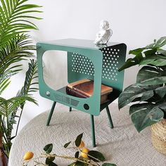 a small green tv sitting on top of a table next to a potted plant