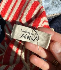 someone is holding up a label that says i belong to ann on the side of their sweater