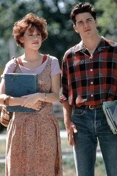 a man and woman standing next to each other in front of a park with trees