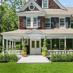 a large house with white trim and green shutters on the front door is shown