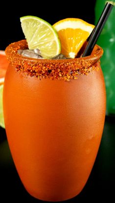 a close up of a drink in a glass with orange and limes on the side