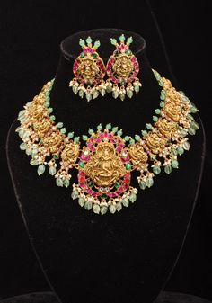 This exquisite necklace set showcases a beautifully crafted lord Krishna adorned with intricate etchings. The pendant, inspired by the lord of divine form radiates serenity and grace, evoking a sense of reverence and admiration, and is accompanied by equally stunning Krishna earrings. The necklace itself is adorned with Lord Krishna and peacock motifs, enhanced by embellished stones and dangling green beads. Note: This jewelry has no precious metals or stones.  Note: Some of the pics are close-u Spiritual Temple Necklace With Gemstones For Festive Occasions, Spiritual Festive Necklace With Intricate Design, Spiritual Temple Necklace With Intricate Design For Celebrations, Spiritual Necklace With Intricate Design For Festive Occasions, Spiritual Temple Necklace For Celebration With Intricate Design, Ceremonial Jewelry With Detachable Pendant, Ceremonial Elegant Jewelry With Detachable Pendant, Spiritual Gemstone Jewelry For Festivals, Fusion Style Necklace With 17 Jewels For Festivals