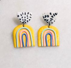 two pairs of yellow and blue earrings with rainbows on them, sitting next to each other